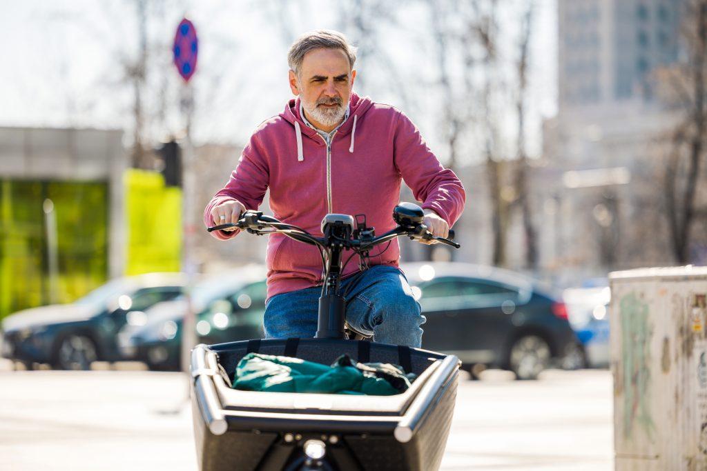 Älterer Mann fährt mit einem Lastenfahrrad in der Stadt